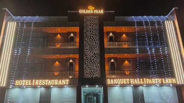 A hotel with a modern facade, featuring illuminated signs for 'Hotel Restaurant' and 'Banquet Hall Party Lawn.' - Hotel Golden Peak (Tanakpur)