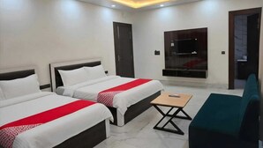 A hotel room with two beds, a TV, ceiling fans, and a small table. - Hotel Golden Peak (Tanakpur)