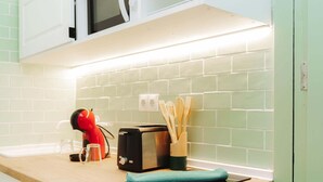 Una cocina con microondas, tostadora y un portalápices de madera en la encimera.