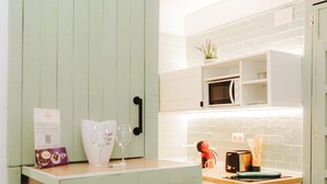 Una cocina con armarios verde claro, encimera blanca, microondas y tostadora.