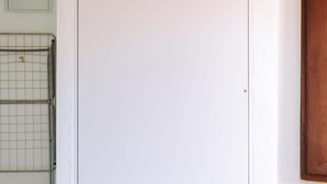Une porte blanche avec une structure en treillis métallique sur le côté gauche, un panneau en bois sur le côté droit, et un petit objet rectangulaire fixé au mur au-dessus de la porte.