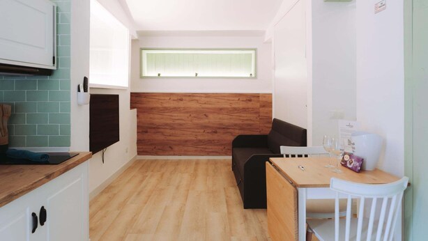 Une cuisine compacte dotée d’un plan de travail en bois, d’un four encastré et d’une fenêtre située au-dessus de l’évier.