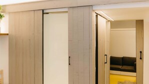 Una stanza con una porta scorrevole, un divano e un pavimento giallo.