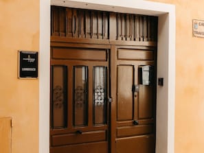 A brown double door with a keyhole and a mail slot, a sign for 'Harbor's Light' apartments, and a 'CAMPUS TRAVEL' sign on the wall. - Lambrusco Harbor's Light (La Vila Joiosa)