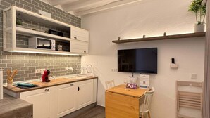Una cucina moderna con mobili bianchi, un piano di lavoro in legno, un forno a microonde integrato e un'area pranzo con un tappeto giallo.