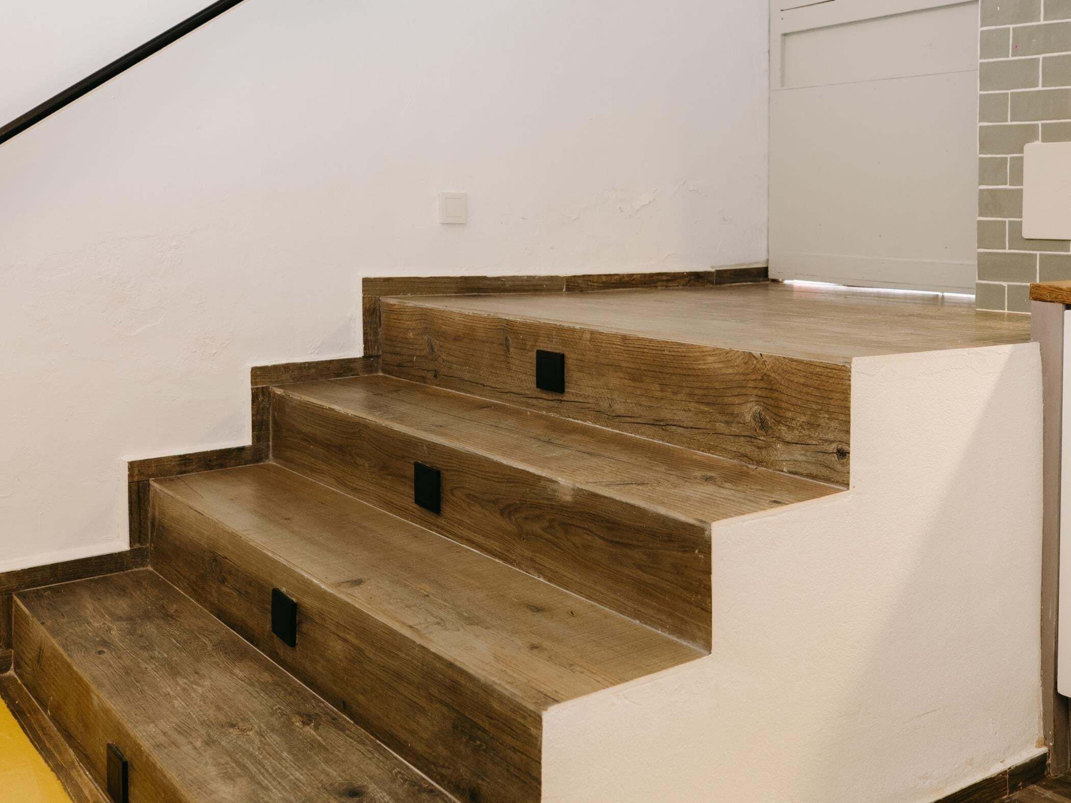 A staircase with wooden steps and a white wall.