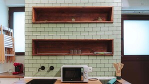 Una cocina con microondas, repisas de madera y un lavamanos.
