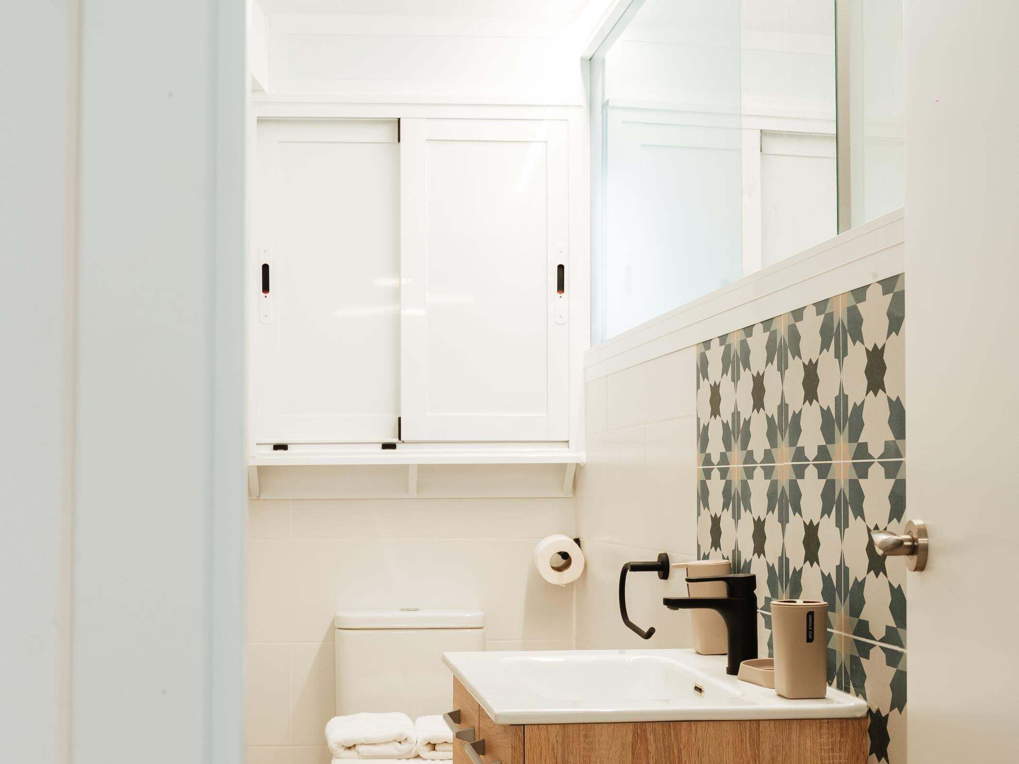 Een badkamer met toilet, wastafel en handdoekstapel.