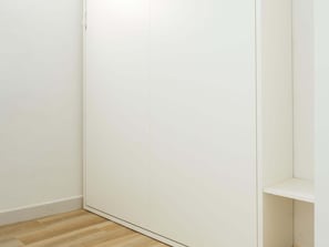 A room with a wooden floor, a white wardrobe, and a white shelf unit. - Verdil Harbor's Light (La Vila Joiosa)