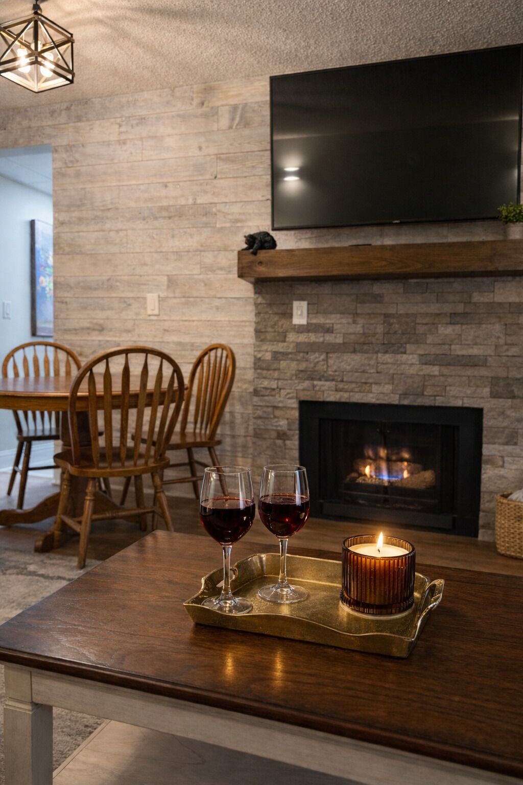 A modern living room with a fireplace, a flat-screen TV mounted above it, and a dining area with wooden chairs and a table.