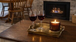 Ein modernes Wohnzimmer mit Kamin, einem flachbildfernseher darüber und einem Essbereich mit Holzsesseln und Tisch.