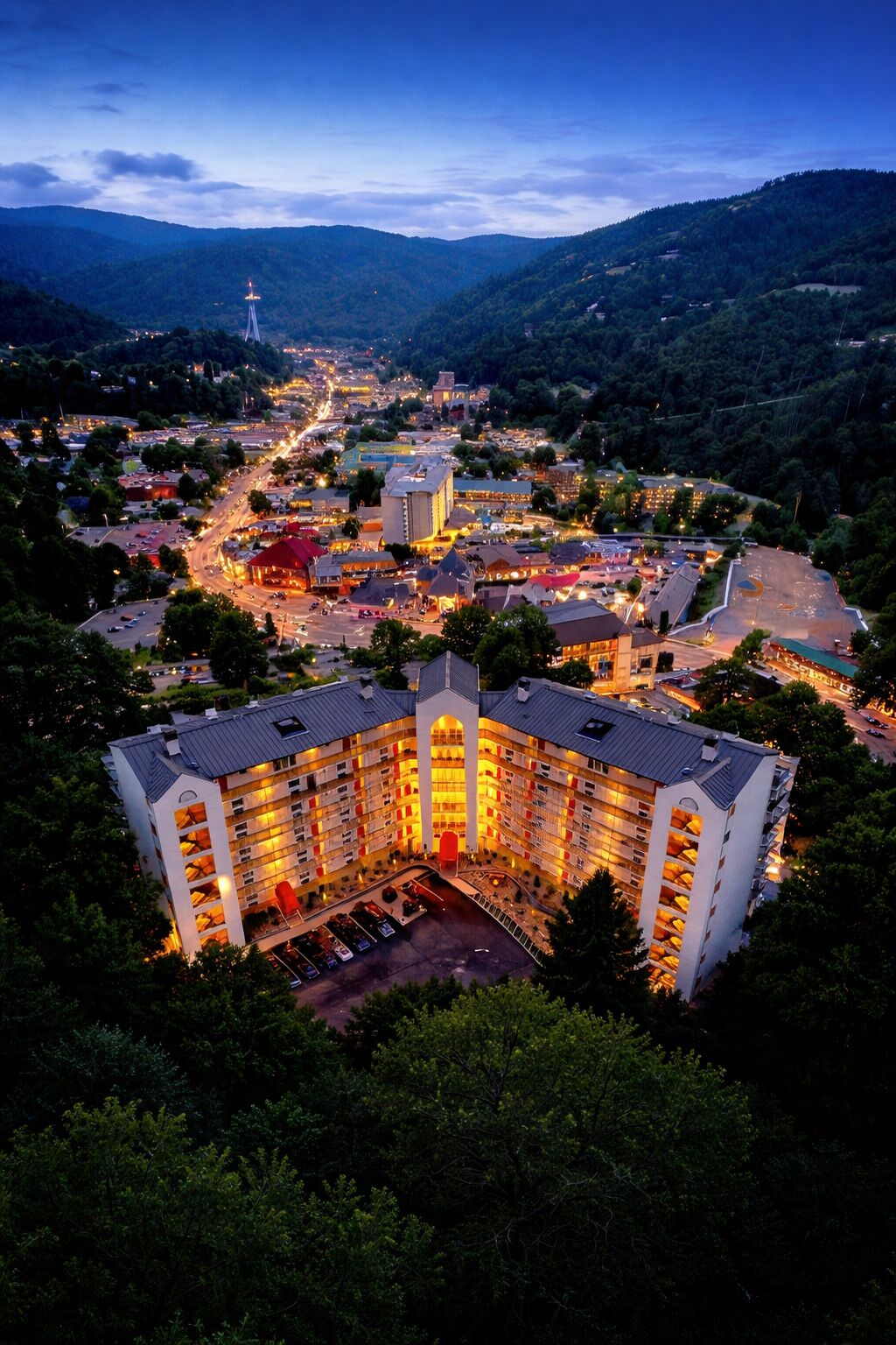 A multi-story hotel with a central courtyard, surrounded by a mountainous landscape.