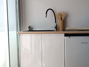 A kitchen with a dishwasher, a sink with a faucet, wooden utensils in a holder, and a small plant on the counter. - Syrah Harbor's Light (La Vila Joiosa)