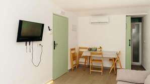 A room with a TV, a dining table with chairs, a sofa, and an air conditioning unit. - Malvasia Harbor's Light (La Vila Joiosa)