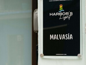 A window with a sign for 'Harbor's Light Malvasia' and a website address 'HARBORSLIGHT.COM'. - Malvasia Harbor's Light (La Vila Joiosa)