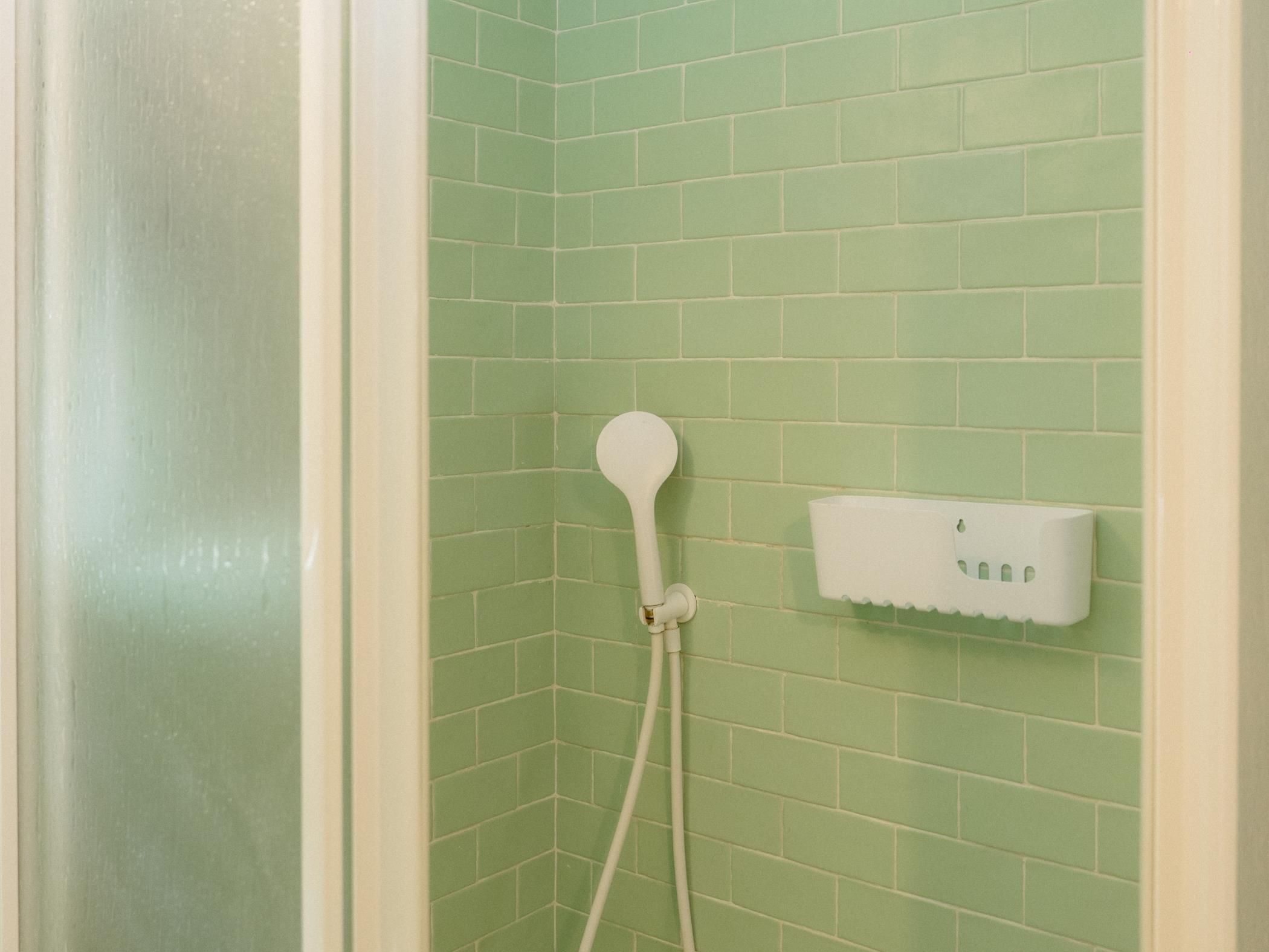 Una ducha con cabezal de ducha de mano y panel de control en la pared.