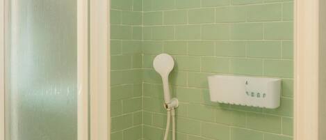 Una ducha con cabezal de ducha de mano y panel de control en la pared.