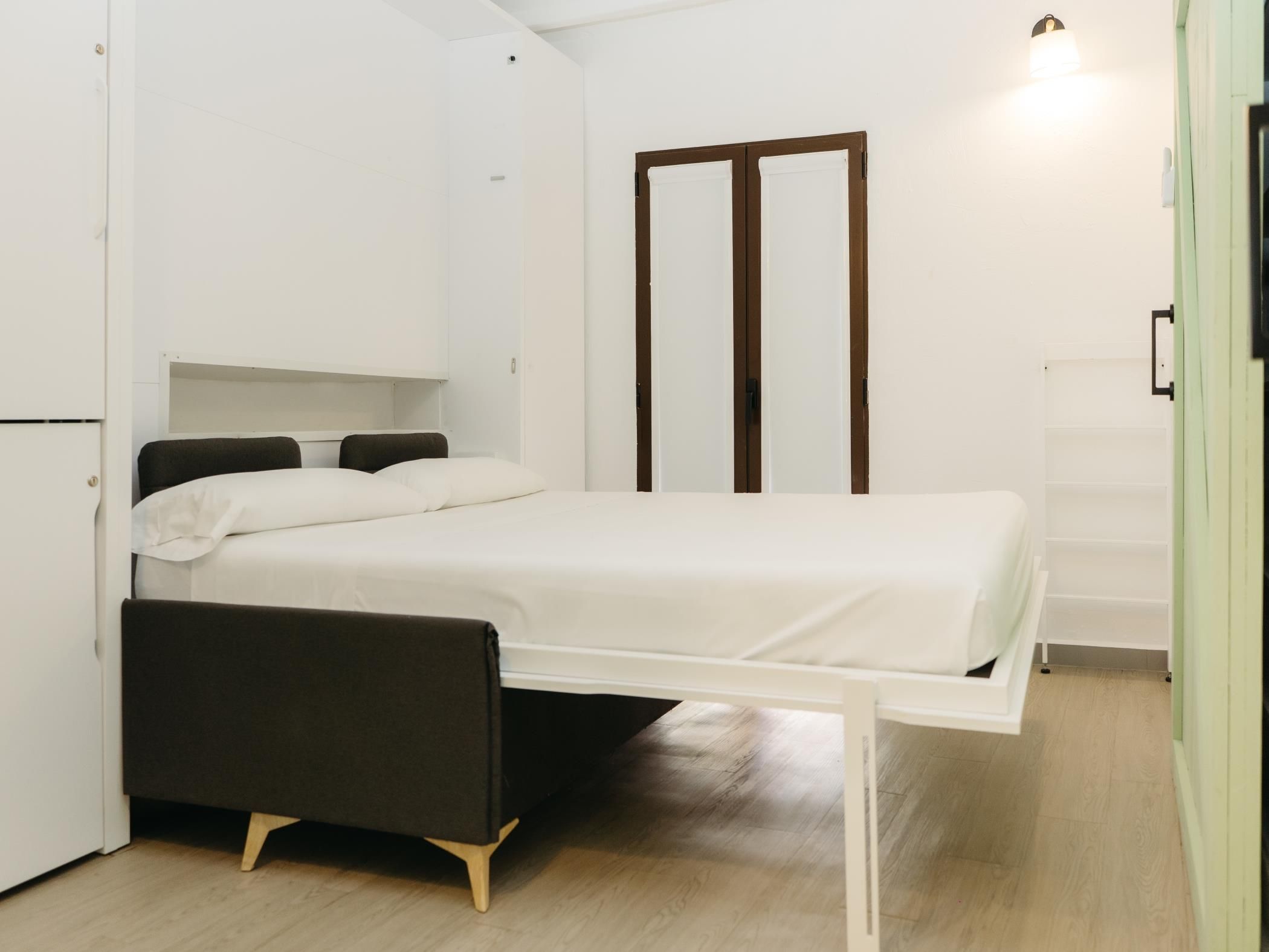 A compact room with a bed, a desk, and a wardrobe.