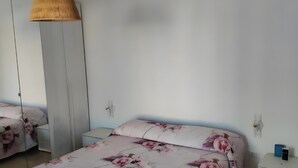 A bedroom with a bed, bedside tables, a wardrobe, and a hanging light fixture. - Villa 'Regina' with Private Garden and Air Conditioning (Taranto)