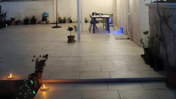 A patio area with a table and chairs, potted plants, and a string of lights. - Villa 'Regina' with Private Garden and Air Conditioning (Taranto)