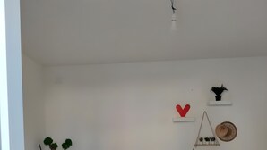 A living room with a white sofa, a small side table, a white shelf with decorative items, and a tiled floor. - Villa 'Regina' with Private Garden and Air Conditioning (Taranto)