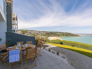 A patio with a table set for breakfast, overlooking a coastal view. - Anchors Rest (St Ives)