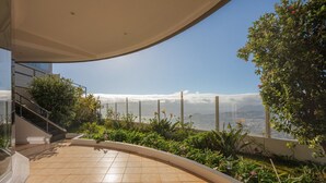 Eine moderne Terrasse im Freien mit gewölbtem Dach, einer Treppe und Blick aufs Meer.