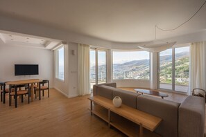 Ein geräumiges Wohnzimmer mit großem Fenster, Essbereich und Flachbildfernseher.
