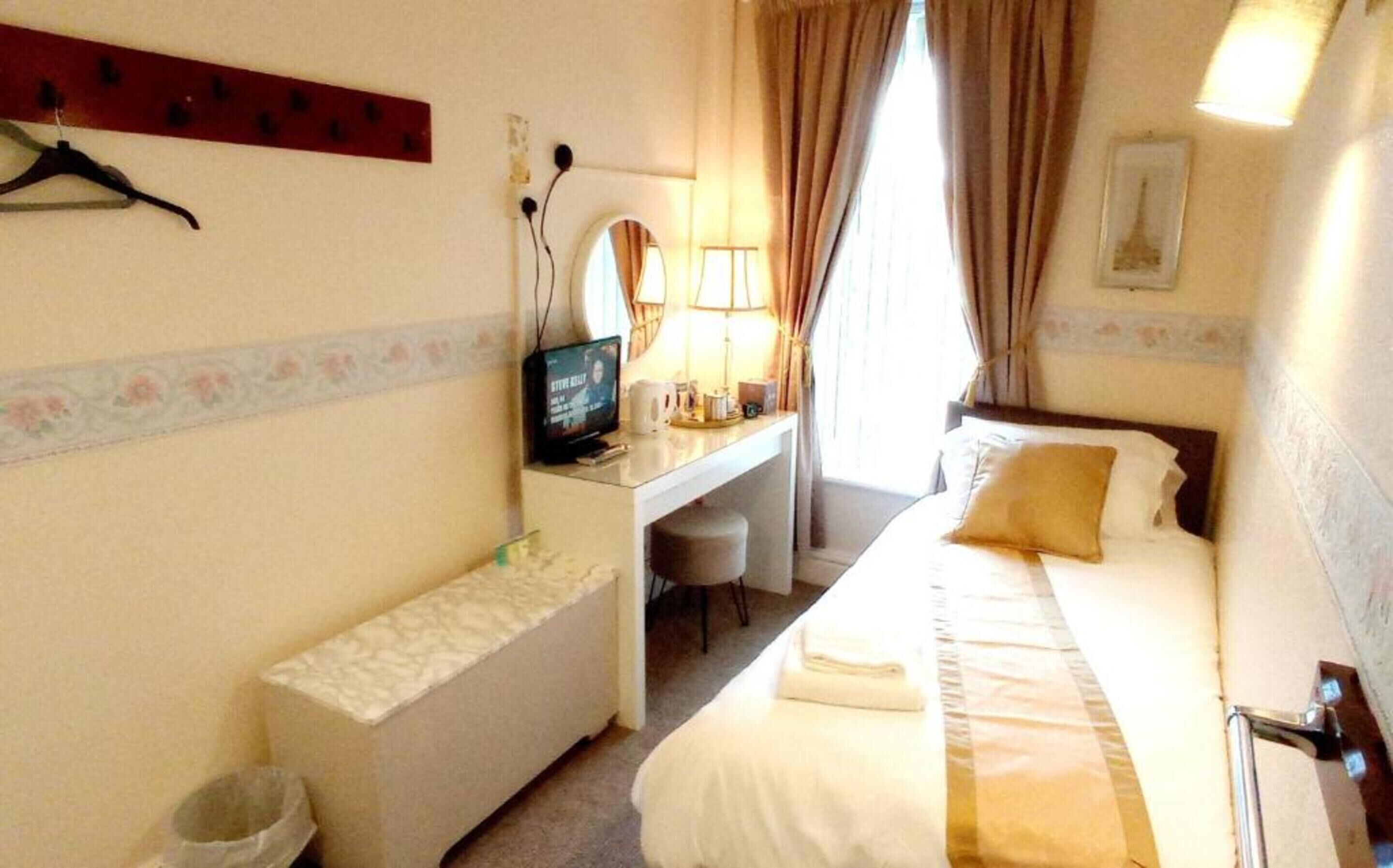 A hotel room with a bed, desk, chair, and a television.