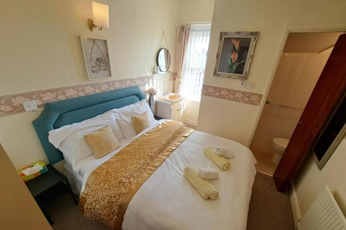 A hotel room with a bed, bedside table, and a bathroom visible through an open door.