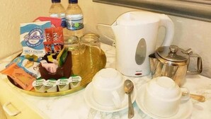 Una bandeja de desayuno con diversos alimentos, una cafetera y un hervidor de tetera sobre una encimera de mármol.