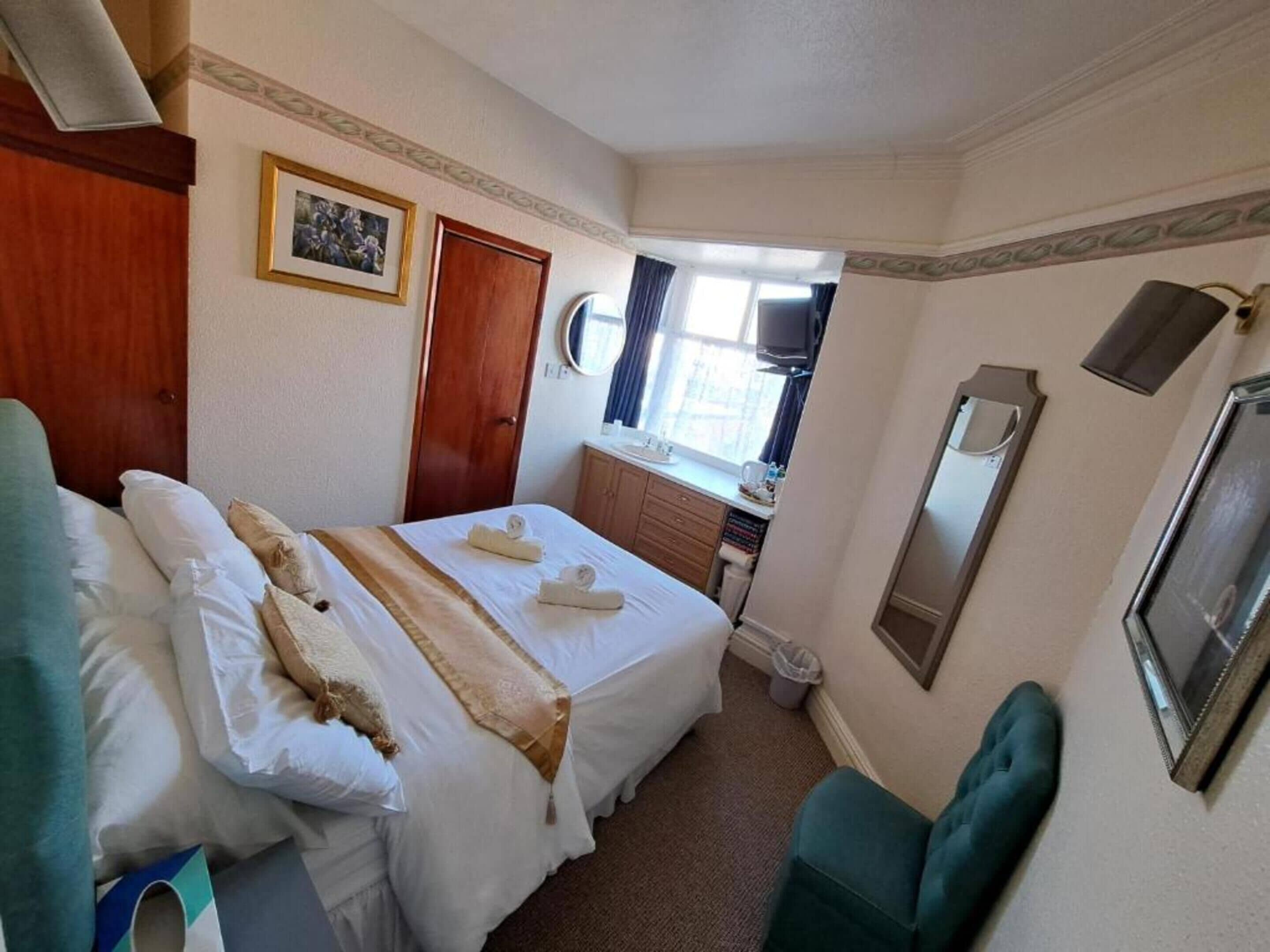 Een hotelkamer met een bed, een dressoir, een spiegel en een raam.