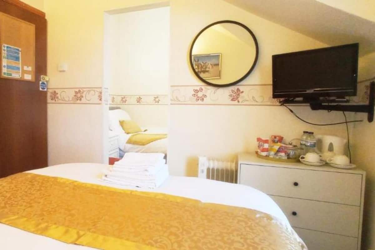 A hotel room with a bed, a dresser, a television, and a door.