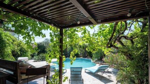 Un espace extérieur abrité comprenant une piscine, des chaises longues et une table.