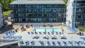 A multi-story hotel with a pool area, outdoor seating, and a view of the surrounding greenery. - Cozy Lake Escape - King Bed • Private Deck (Osage Beach)