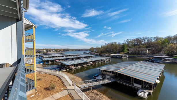 A marina with docked boats, covered structures, and a bridge leading to the docks. - Cozy Lake Escape - King Bed • Private Deck (Osage Beach)
