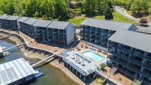 A multi-story hotel with a swimming pool, outdoor seating, and a dock with boats. - Cozy Lake Escape - King Bed • Private Deck (Osage Beach)
