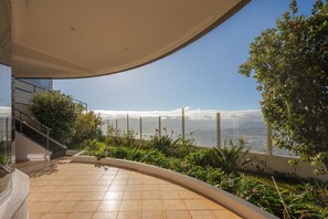 Eine moderne Terrasse im Freien mit gewölbtem Dach, einer Treppe und Blick aufs Meer.