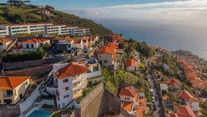A coastal residential area with terraced houses, a swimming pool, and a view of the sea. - 2 Bedroom | 180° View + Balcony | Bathtub (Funchal)