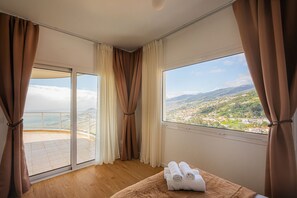 Ein Zimmer mit einem großen Fenster, einem Bett mit brauner Kopfteil und einem Paar Handtüchern auf dem Bett.
