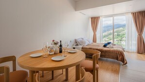 Ett hotellrum med en säng, ett runt träbord med tallrikar och glas, en flaska och en kanna.
