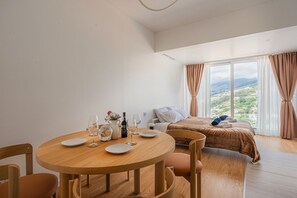 Ein Hotelzimmer mit einem Bett, einem runden Holztisch mit Tellern und Gläsern, einer Flasche und einer Karaffe.