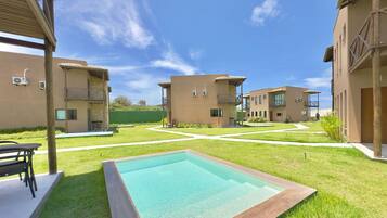 Un patio con piscina, mobiliario exterior y edificios modernos con balcones.