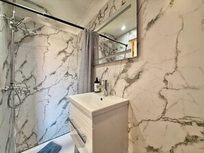 A bathroom with a shower, a sink, and a mirror. - Modern compact Studio APT near City Centre (Essex)