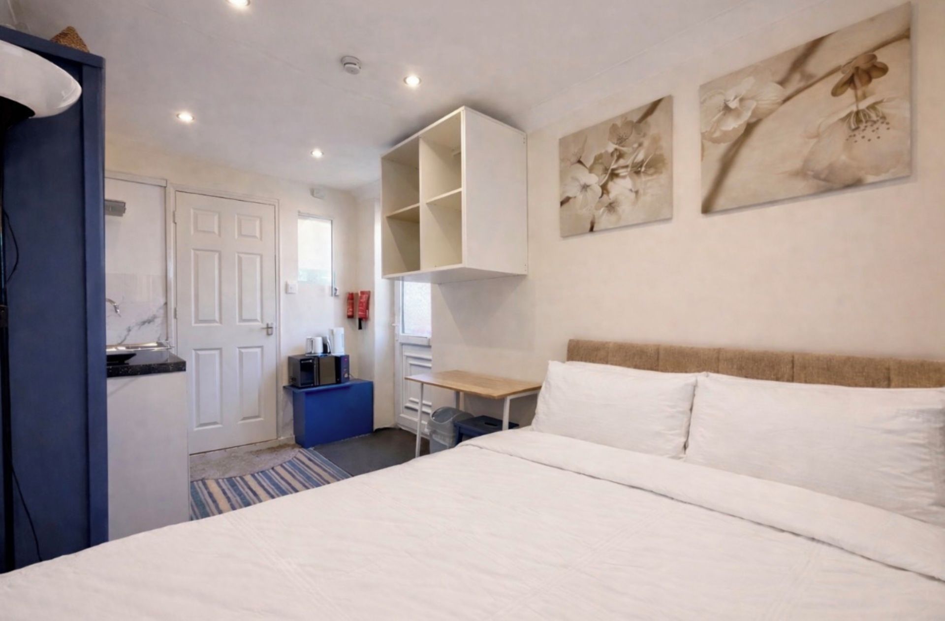 A bedroom with a bed, a desk, and a wardrobe.