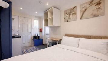 A bedroom with a bed, a desk, and a wardrobe.