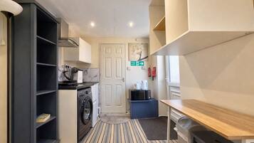 A compact kitchen with a washing machine, microwave, and a small dining table.