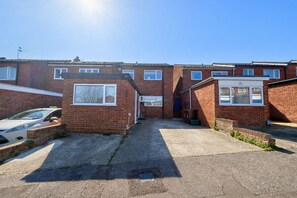 A residential area with brick houses, a paved driveway, and a parked car. - Modern compact Studio APT near City Centre (Essex)