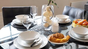 A dining table with white bowls, a glass, a candle, and a basket of oranges. - Brighton Central Seaview Retreat, Steps to the Beach (Brighton and Hove)