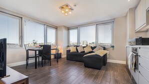 A modern living room with a sofa, dining table, chairs, and a kitchen area with a microwave. - Brighton Central Seaview Retreat, Steps to the Beach (Brighton and Hove)